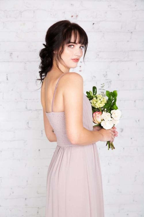 Bridesmaid posing with a low bun updo holding a bouquet of flowers
