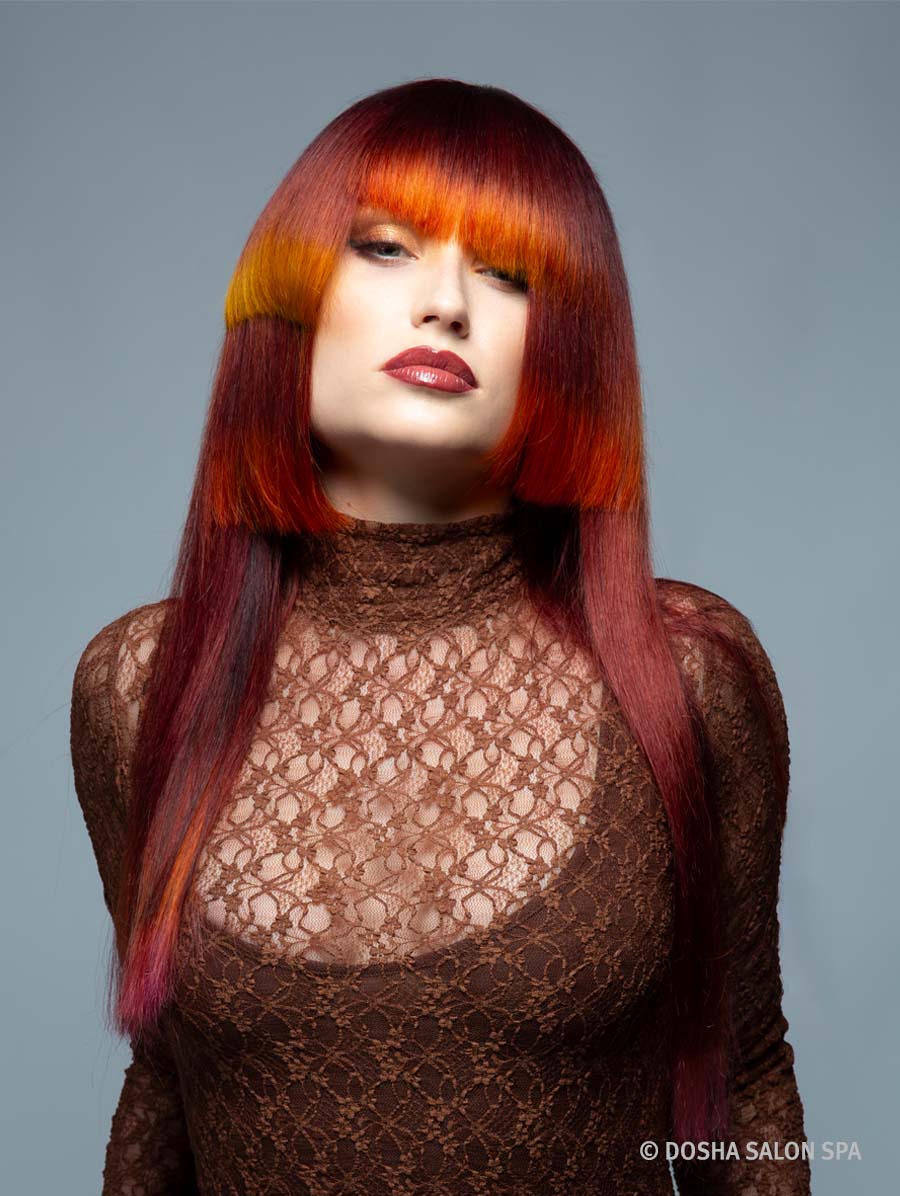 image of a model with hair inspired by the Painted Hills in Oregon with colors of red and orange on an angled cut
