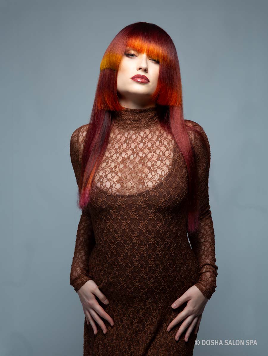 image of a model with hair inspired by the Painted Hills in Oregon with colors of red and orange on an angled cut