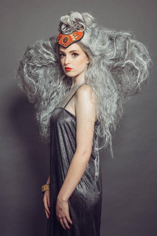 photoshoot of model posing with circus inspired elephant hair and makeup in grey dress and heels