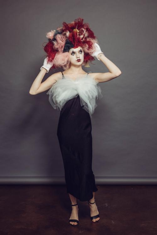 photoshoot of model posing in circus mime inspired makeup and hairstyle in a dress with heels
