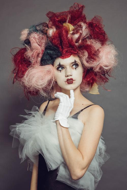 photoshoot of model posing in circus mime inspired makeup and hairstyle in a dress with heels