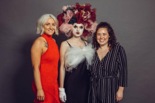 photoshoot of model posing in circus inspired mime makeup and hairstyle in a dress with heels with stylists who created the look