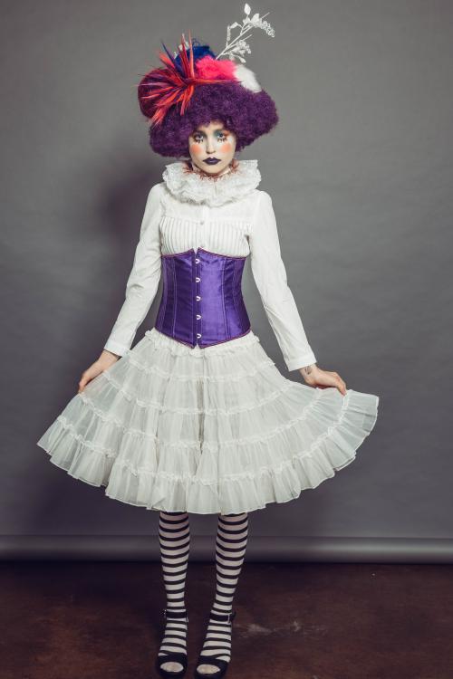 photoshoot of model posing in circus clown inspired makeup and hairstyle in a dress with heels