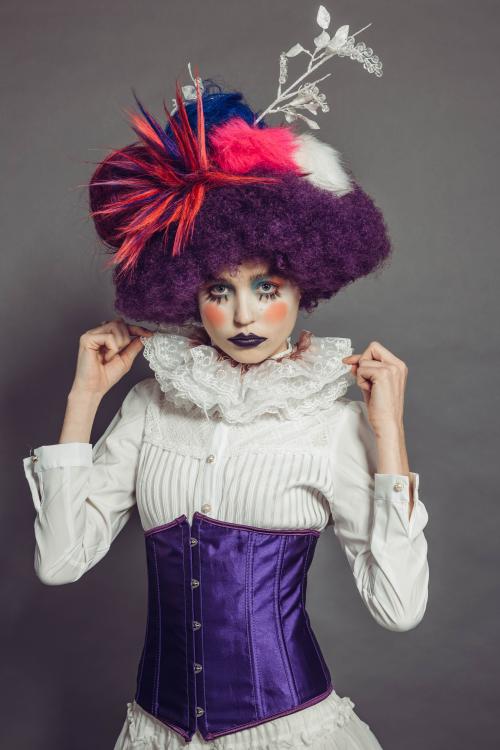 photoshoot of model posing in circus clown inspired makeup and hairstyle in a dress with heels