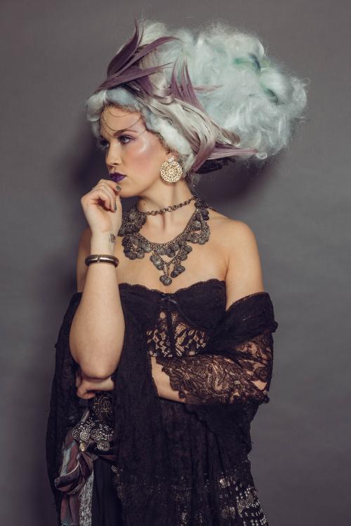 photoshoot of model posing in circus fortune teller inspired makeup wearing a dress and jewlery
