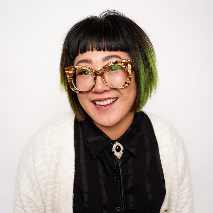 Dosha hairstylist Jessica Watts with green highlights in her hair and chunky glasses.